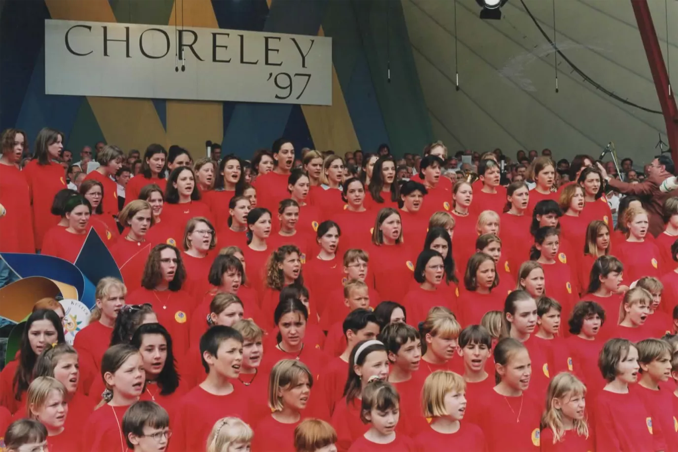 Großer Kinder- und Jugendchor in roten Gewändern beim Choreley-Festival 1997 unter dem Banner CHORELEY '97