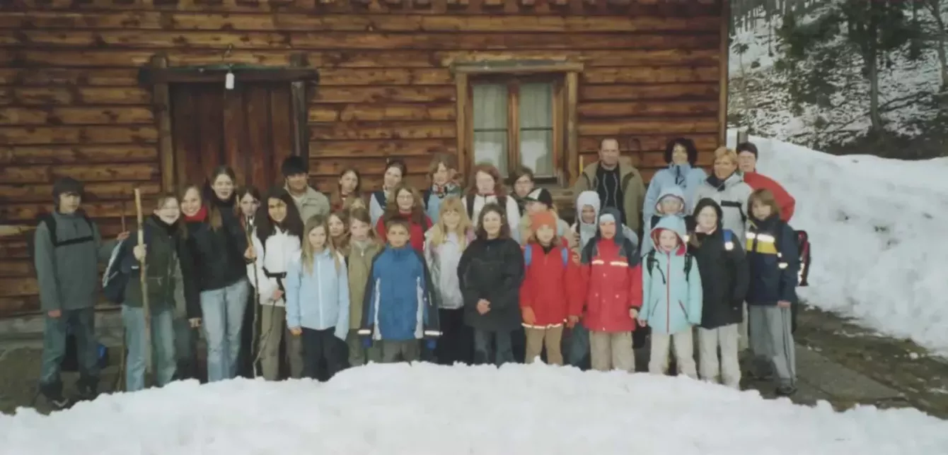 Chorgruppe im Winter vor einer verschneiten Holzhütte, aufgereiht für ein Gruppenfoto