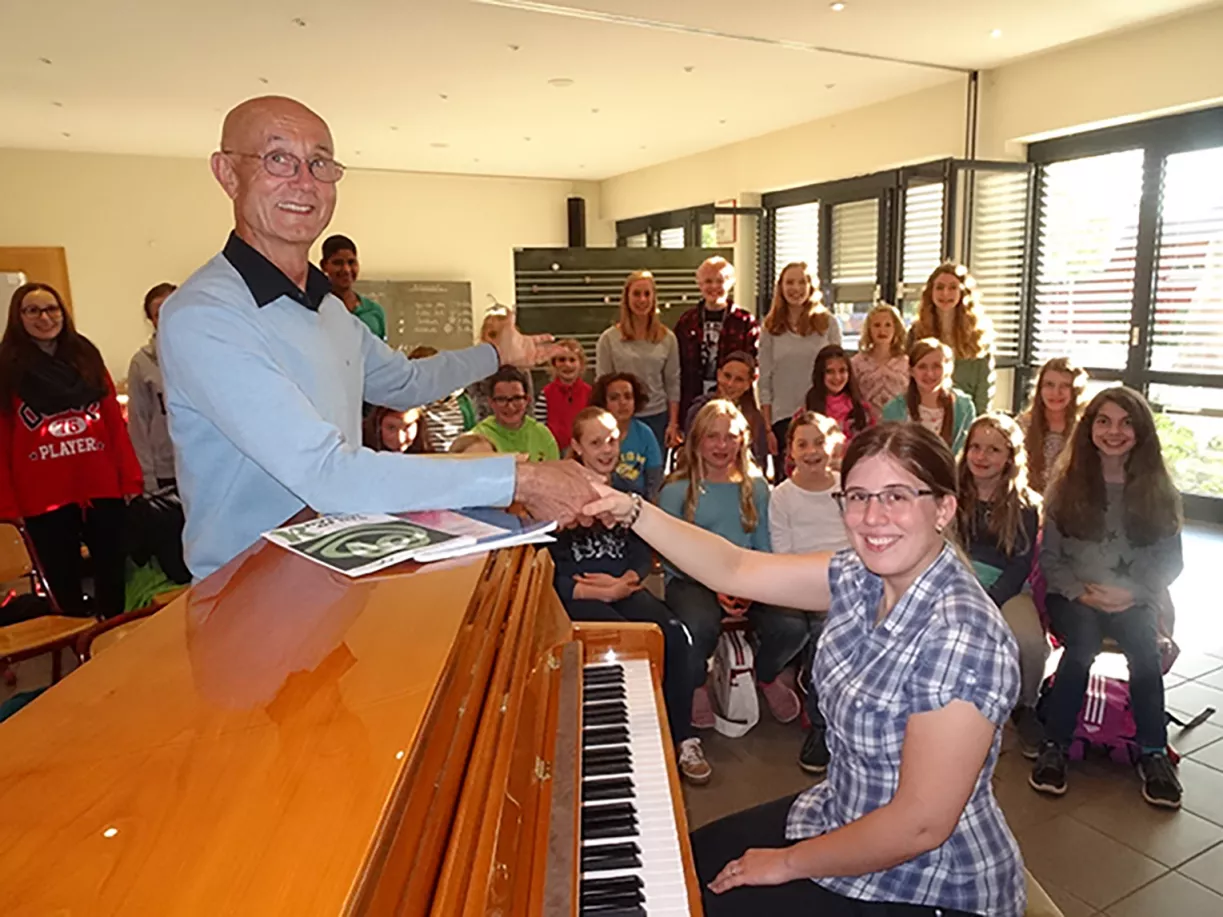 Symbolischer Chorleitungswechsel am Klavier per Handschlag vor dem versammelten Kinderchor