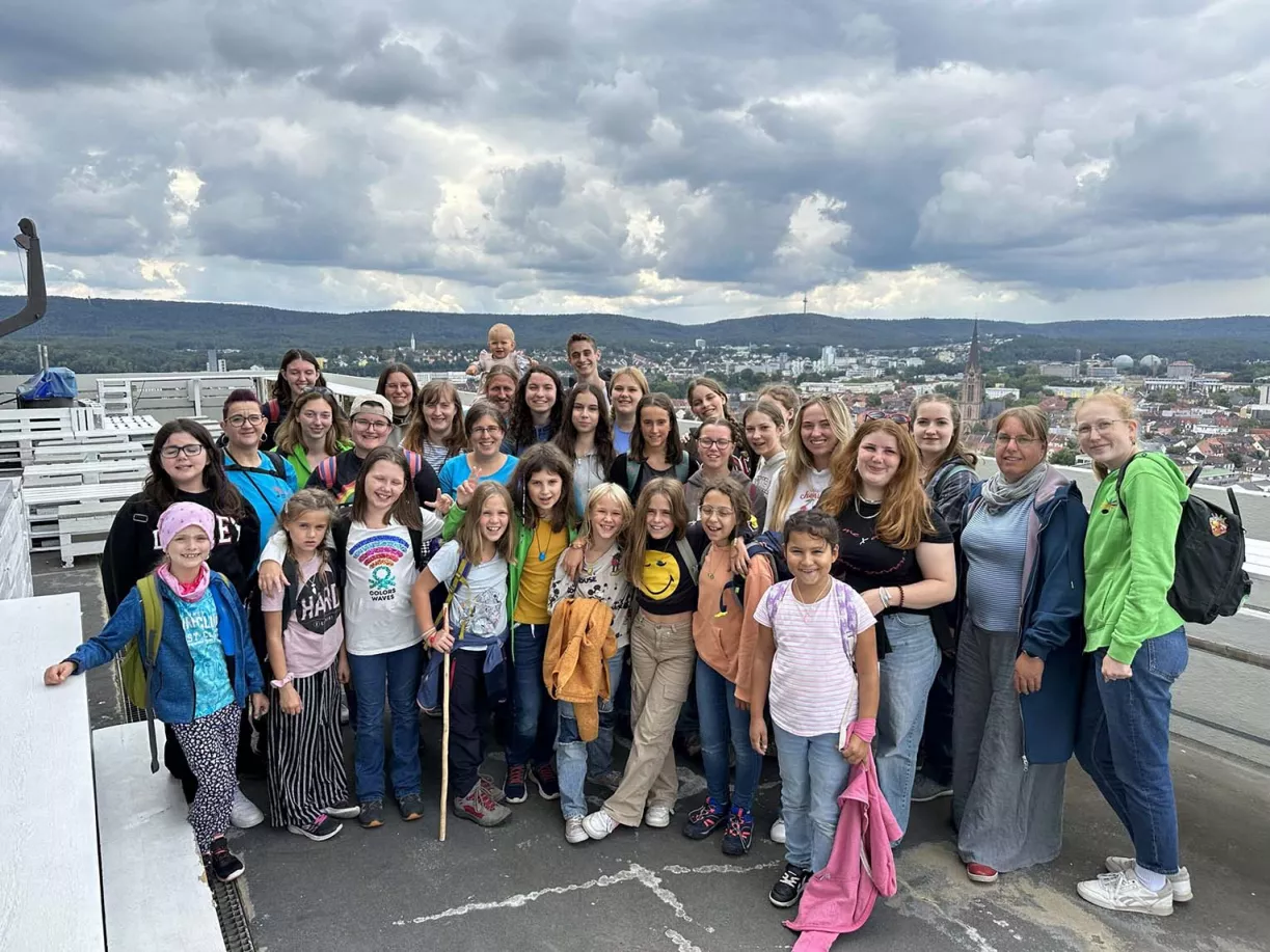 Große Chorgruppe auf einer Aussichtsplattform mit Stadt- und Waldpanorama bei den Chorferien in Trippstadt