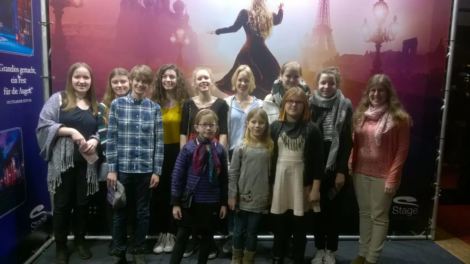 Chorgruppe posiert vor einem Anastasia-Musicalplakat mit Eiffelturm-Motiv im Stage-Theater